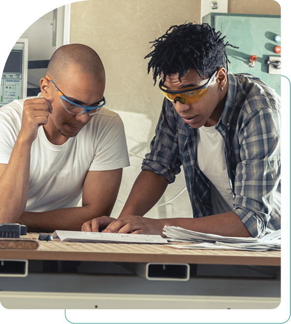 Two men collaborating on a project at a workbench.